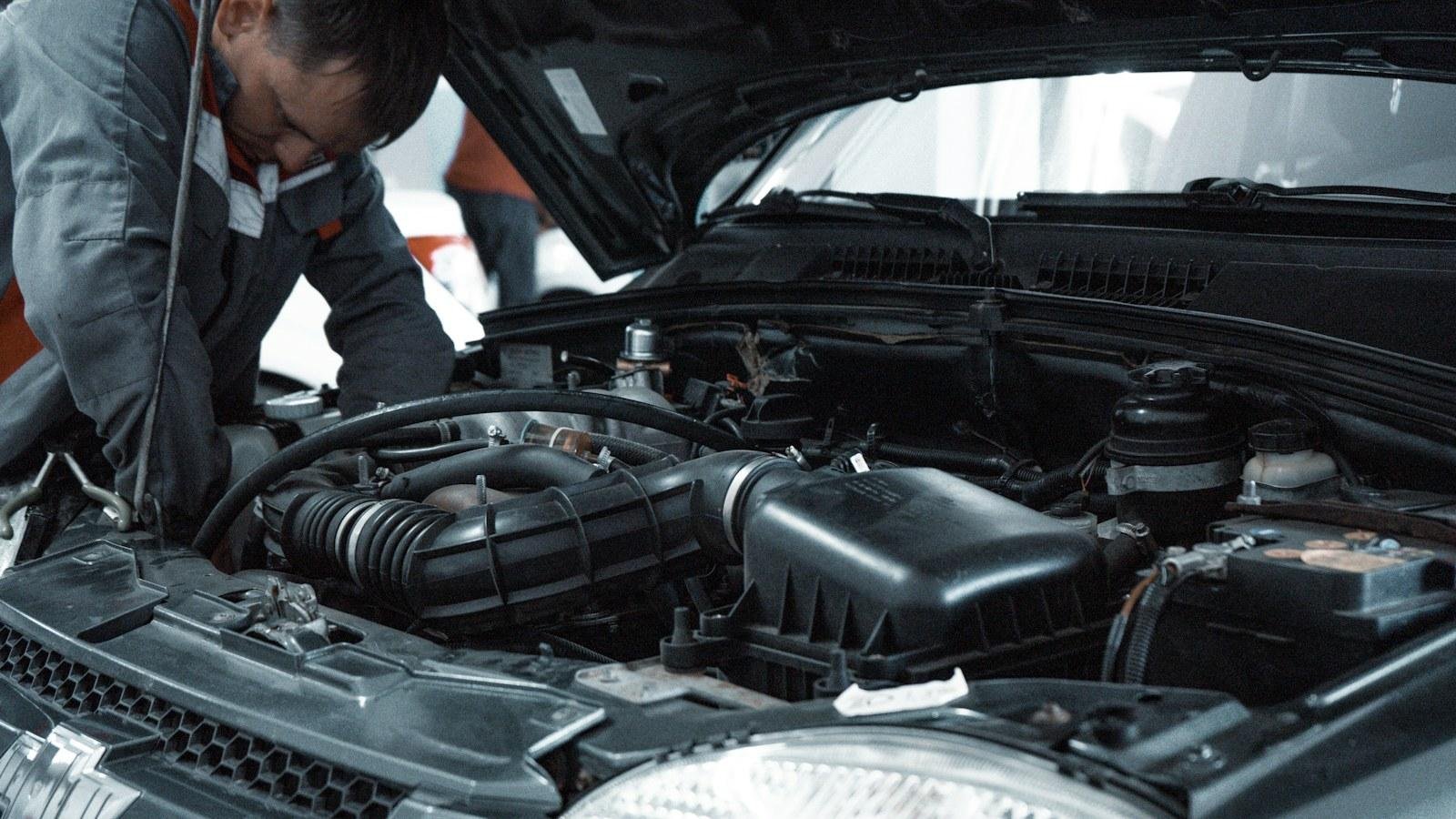 Mechaniker beugt sich über den geöffneten Motorraum eines Autos